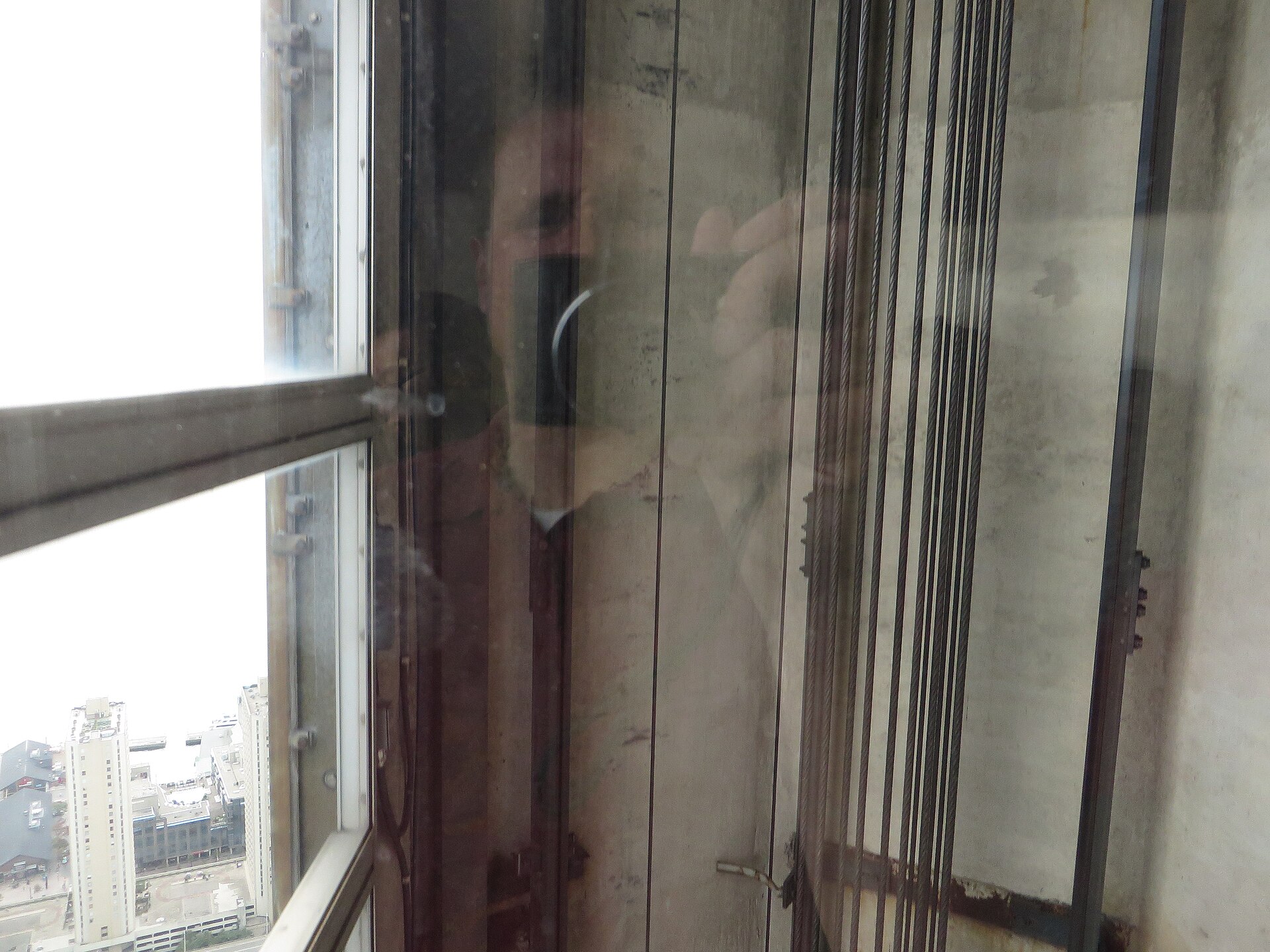 Inside the glass-front elevator car looking down the shaft